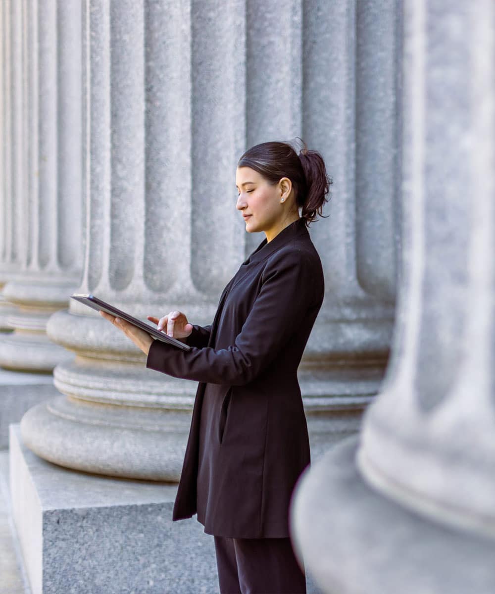 female government worker standing in in front of giant marble columns outside a government building