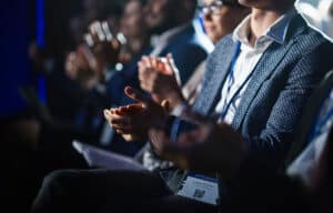 Close Up on Hands of a Crowd of People Clapping in Dark Conference Hall During a Motivational Keynote Presentation