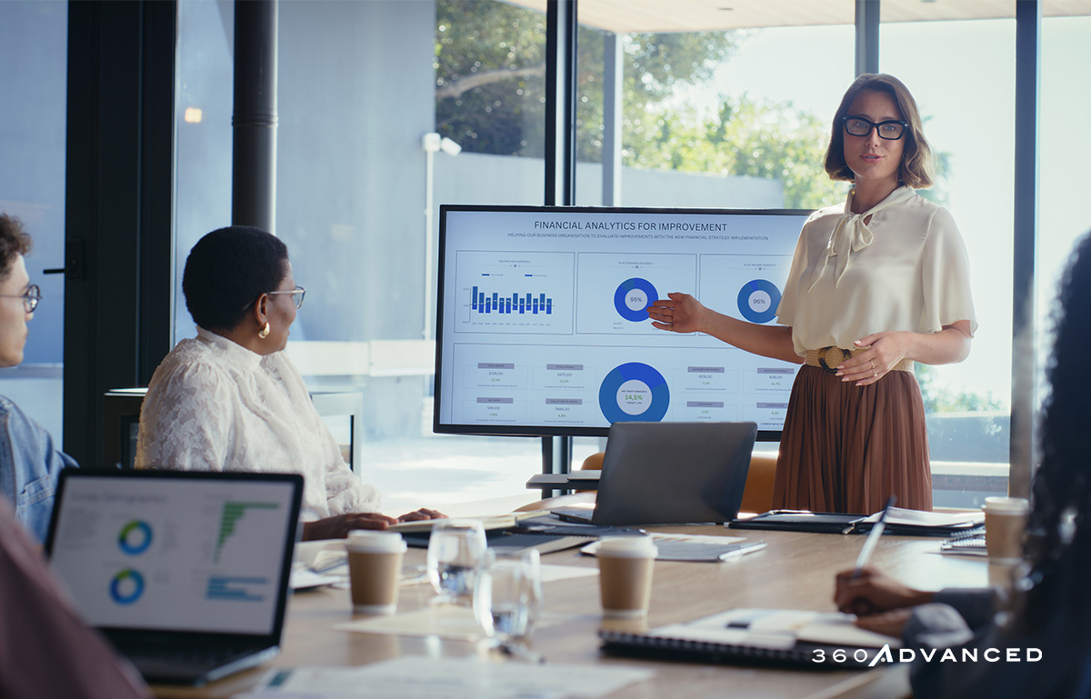 Woman presenting on a monitor for analytics, talk with team, charts on monitor.