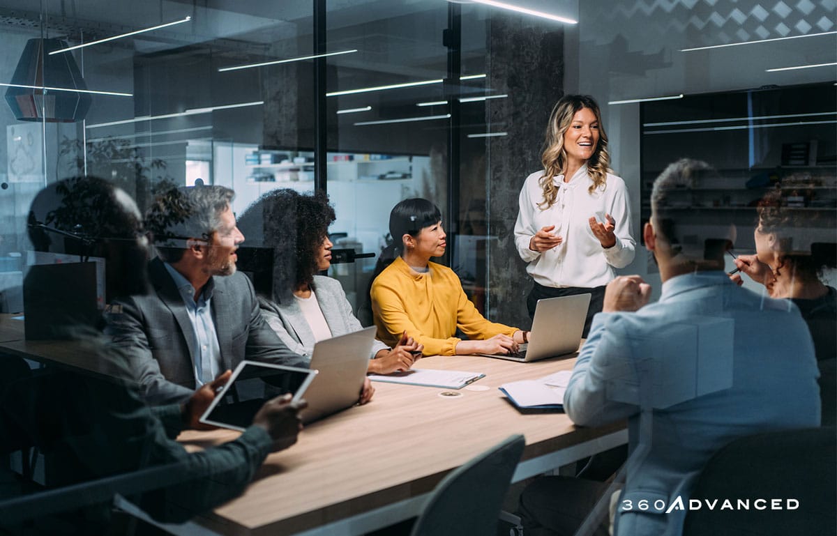 Team of professionals during a meeting, sitting at a conference table in a glass-walled room