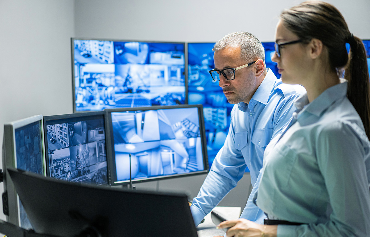 Professionals in Discussion in a private office with multiple security screens in view