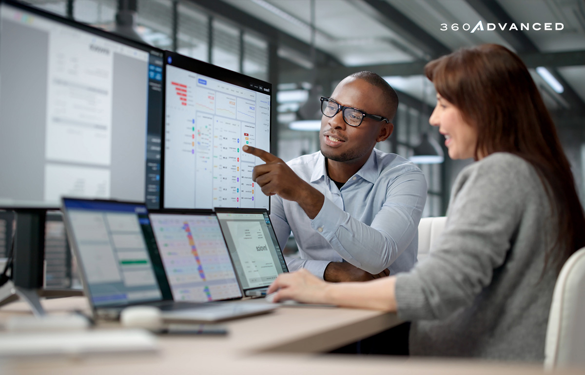 Two Professionals Analyzing Data on Multiple Computer Screens
