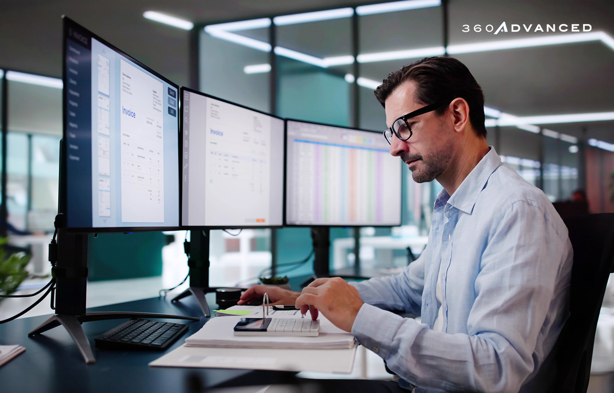 Business professional man working at a desk in front of multiple computer monitors